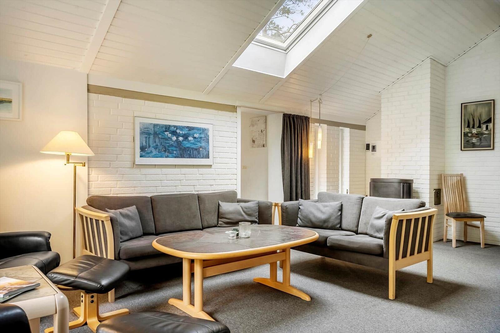 Wohnzimmer mit grauen Sofas, Holztisch und Dachfenster.