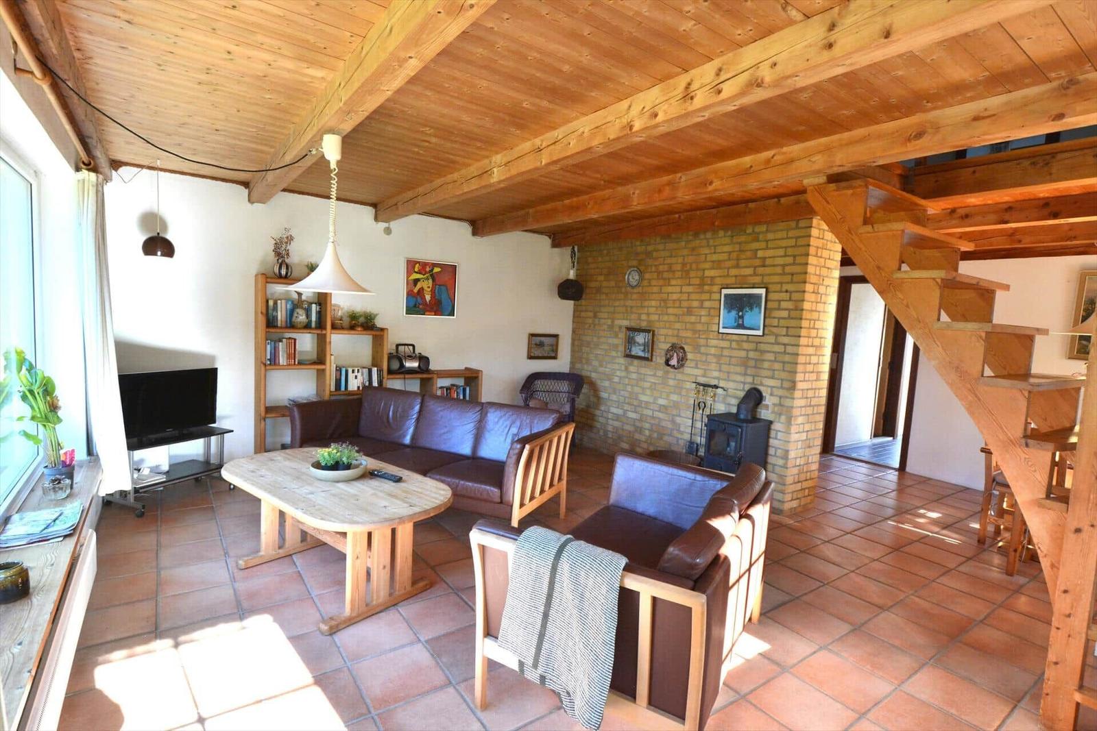 Wohnzimmer mit Holzdecke, Sofa, Tisch und Kamin