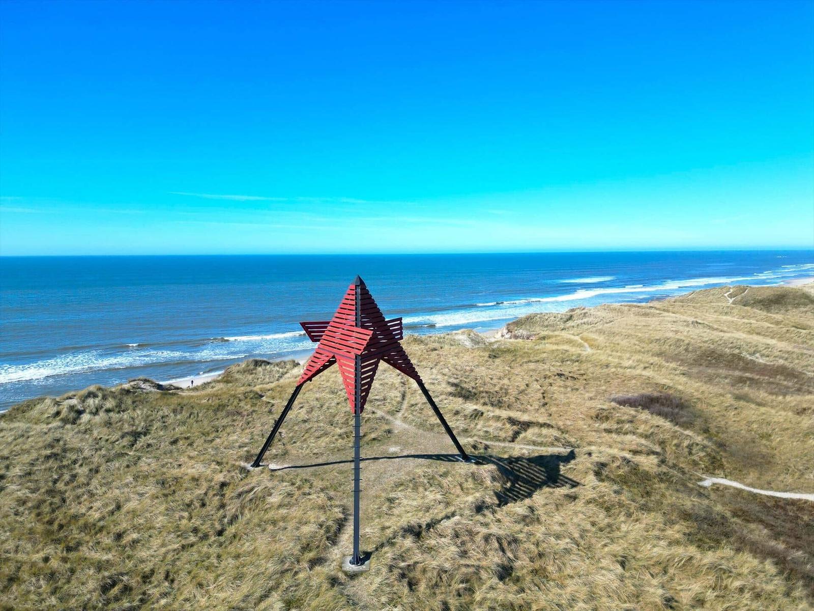 Roter Stern auf Dünen mit Blick auf das Meer und den Strand.