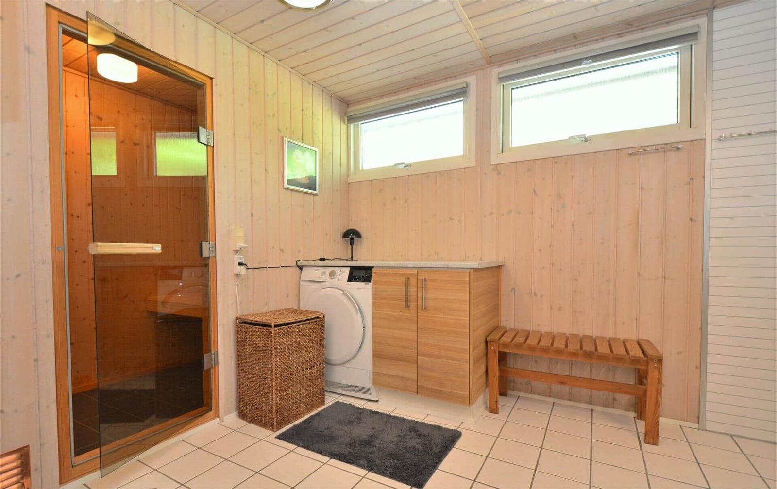 Wohnraum mit Sauna, Waschmaschine und Holzbank.