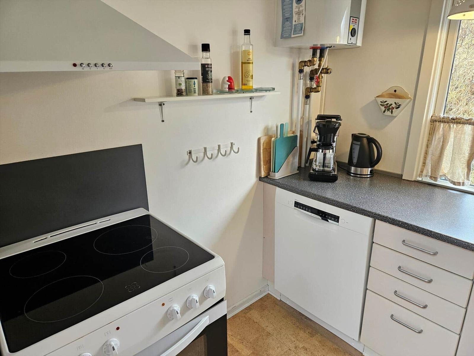 Küche mit Kochfeld, Spüle, Kaffeemaschine und Wasserkocher.