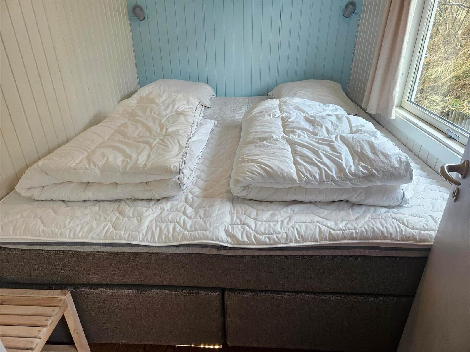 Schlafzimmer mit Bett, weißen Bettwäsche und Fenster