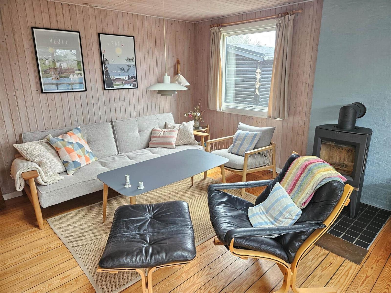 Wohnzimmer mit Sofa, Sessel und Kaminofen an Wand.