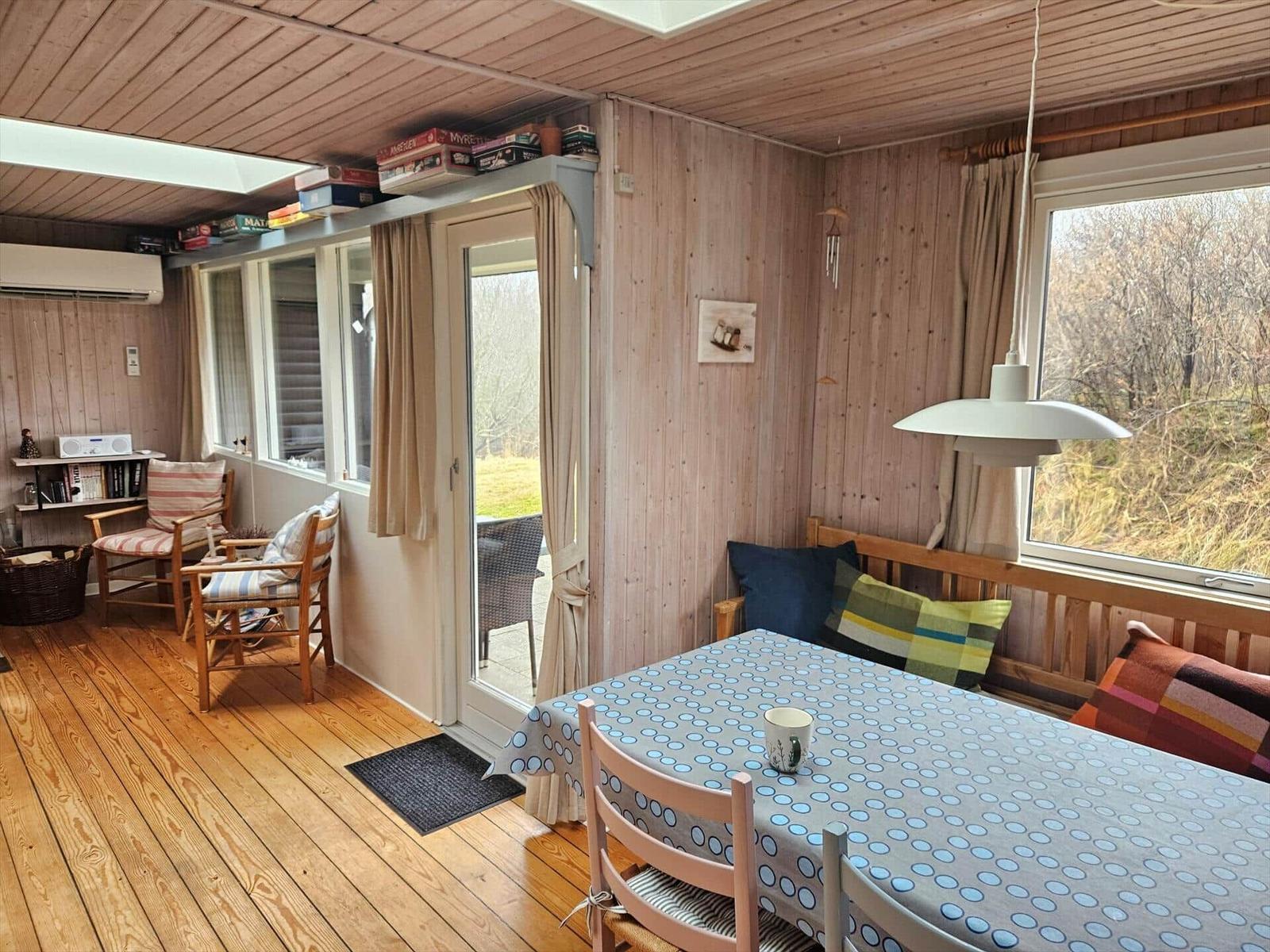 Essbereich mit Tisch, Stühlen und Fensterblick. Holzdecke, Boden und Wände.