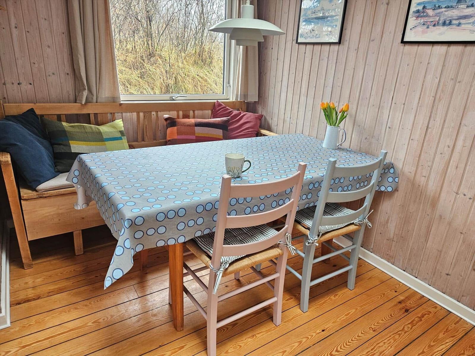 Esszimmer mit Holztisch, Stühlen und Fensterblick auf Grasland.