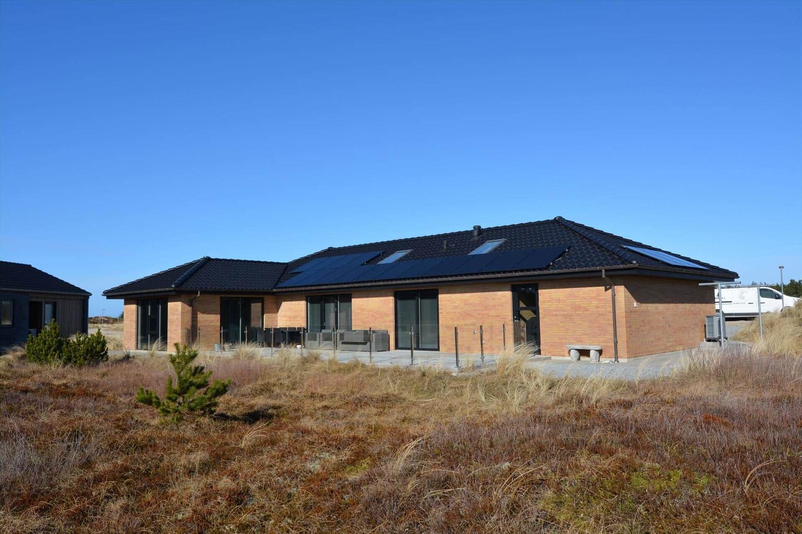 Moderne Villa mit Solaranlage und großem Terrassenbereich im Freien.