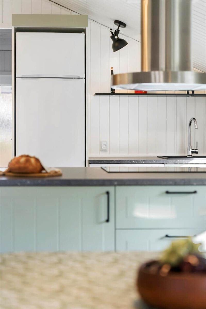 Küche mit weißen Schränken, Kühlschrank und Edelstahl-Armatur.