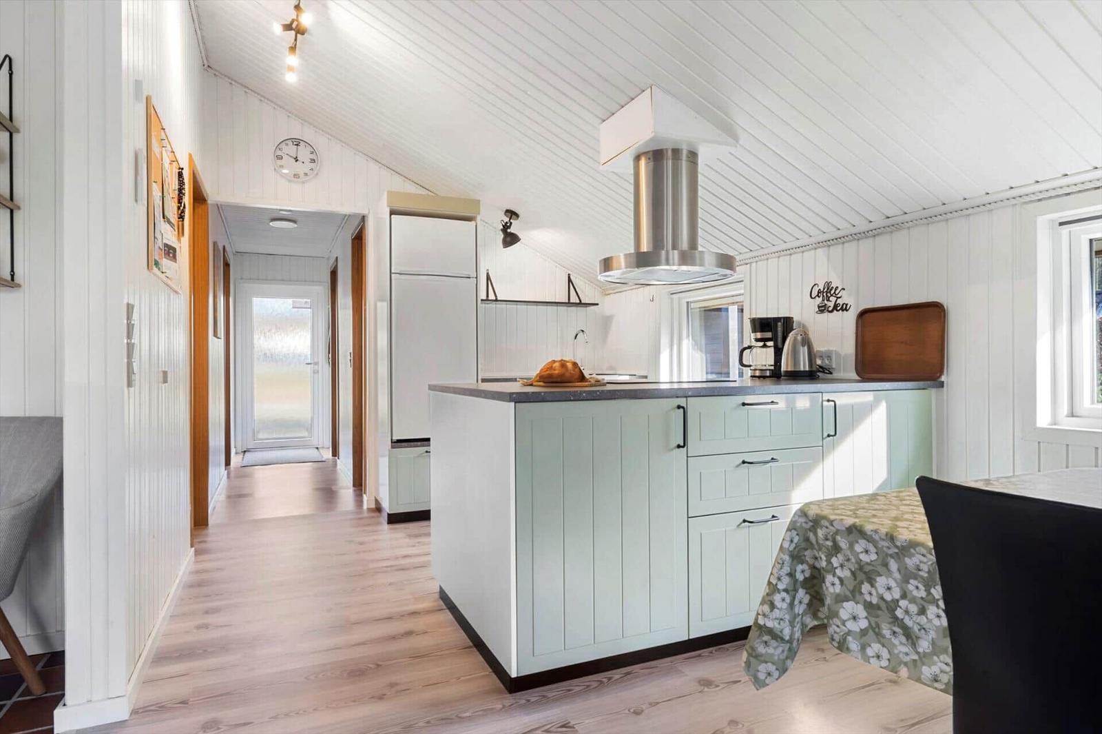 Küche mit Arbeitsplatte, Kühlschrank und Dunstabzug.