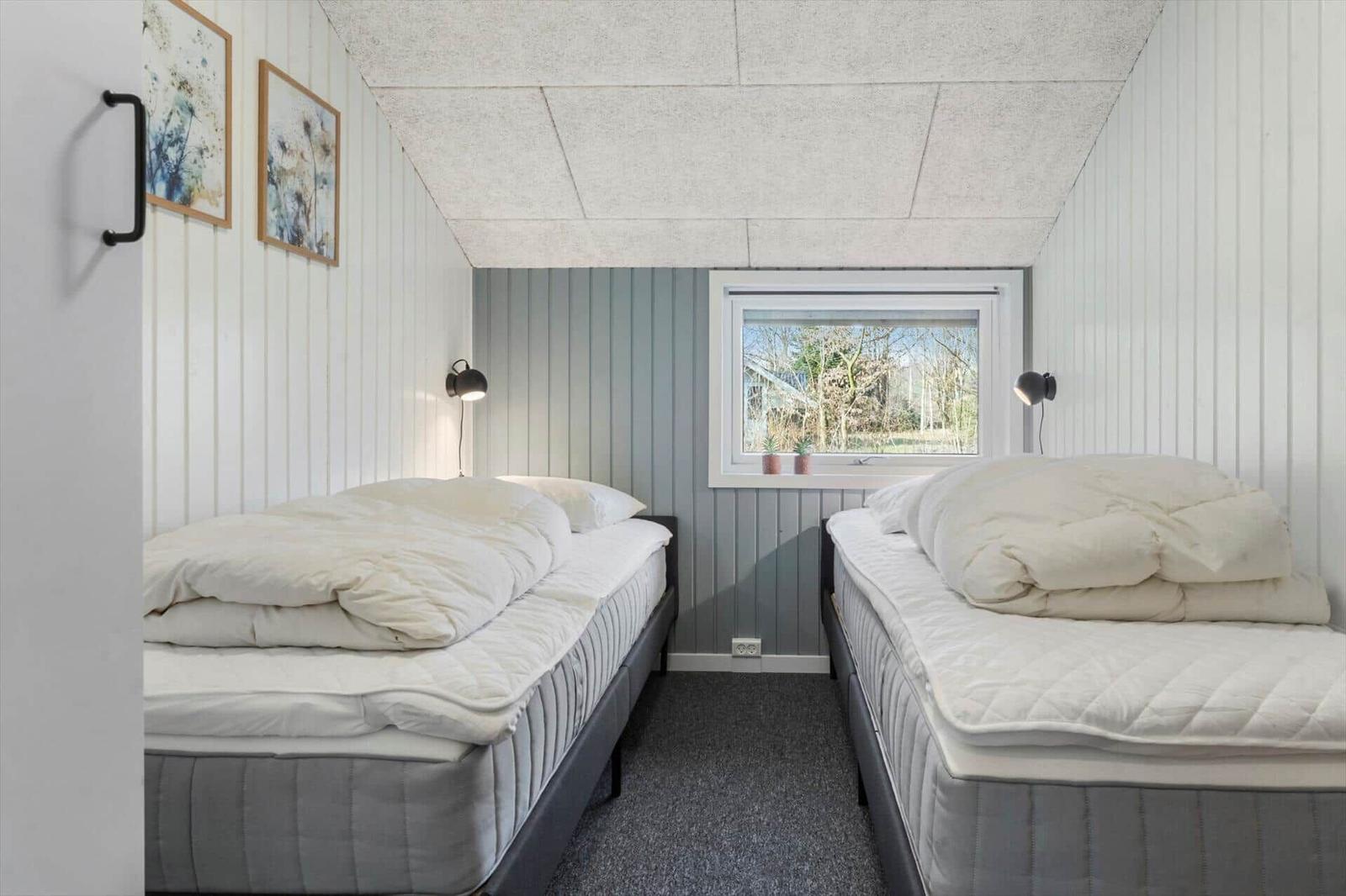 Zwei Betten in einem Raum mit Fenster und Wandbildern.