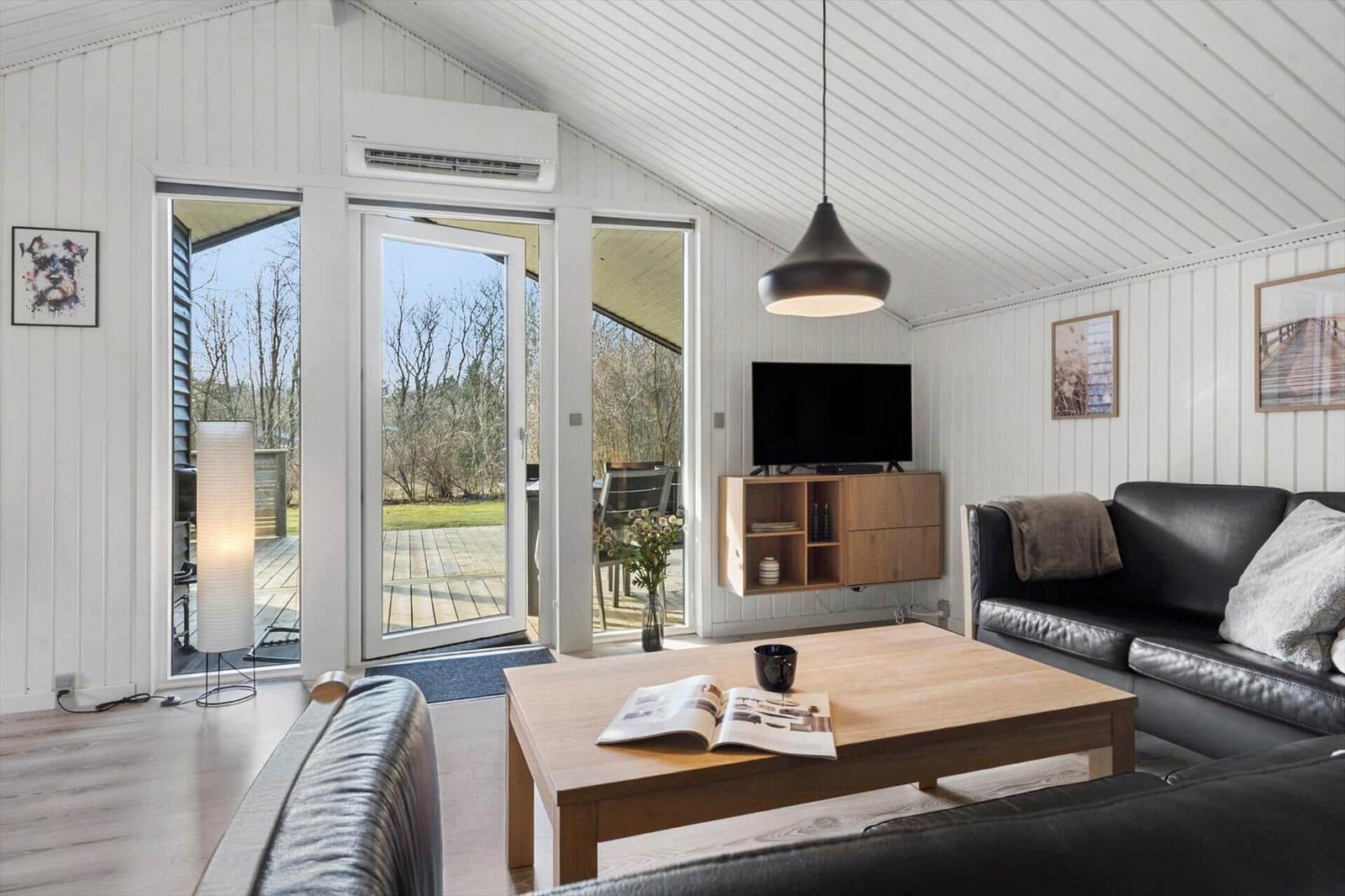 Wohnzimmer mit Sofa, Couchtisch und TV. Große Glastüren führen auf die Terrasse.