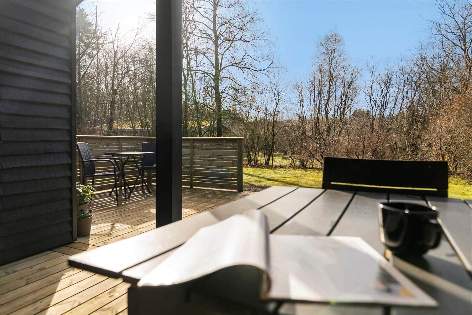 Terrasse mit Tisch, Stühlen und Blick in den Wald.