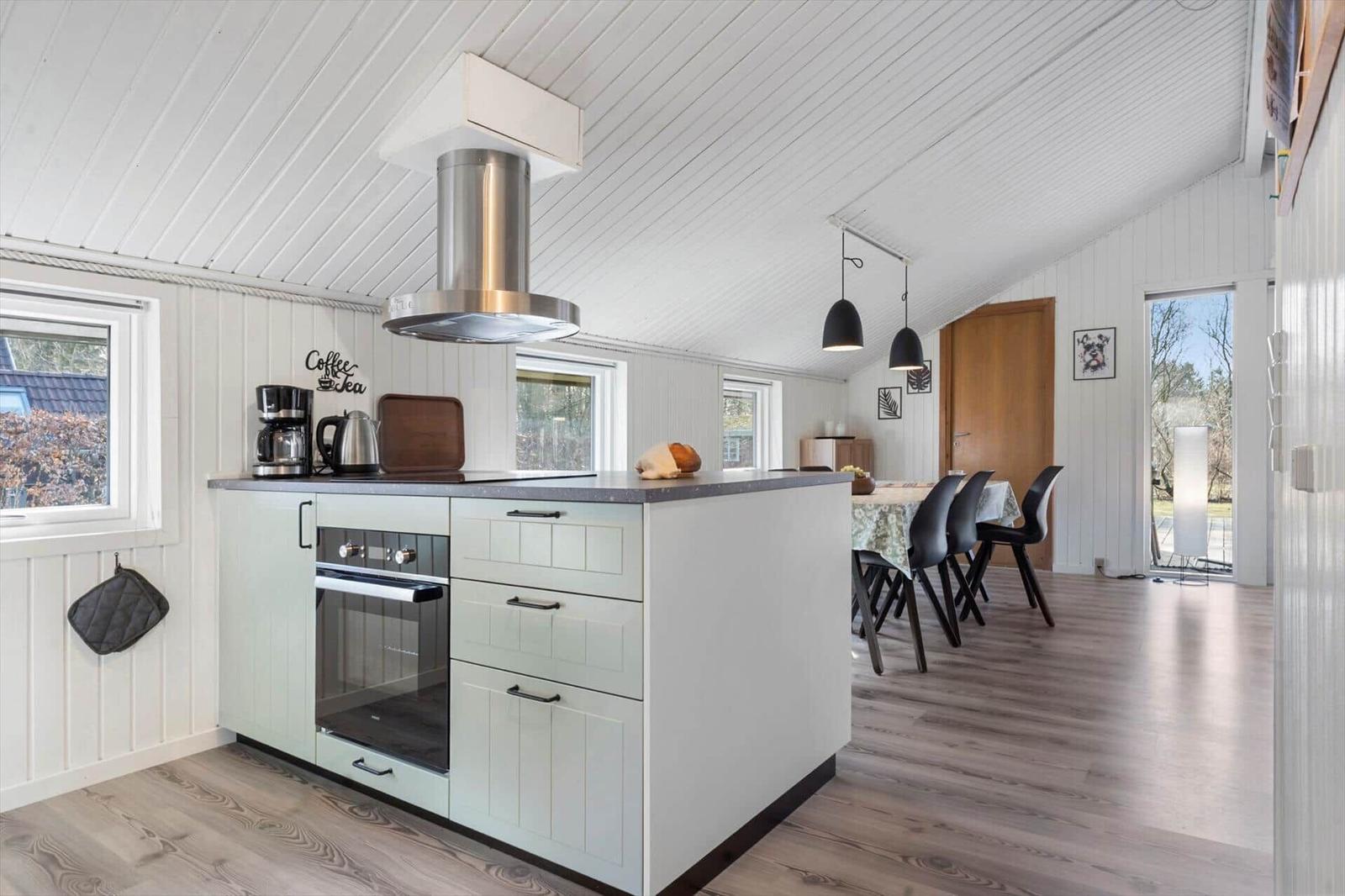 Küche mit Insel, Dunstabzugshaube und Essbereich mit Tisch und Stühlen.