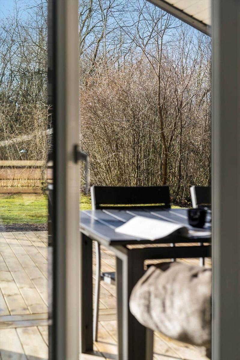 Terrasse mit Tisch und Stühlen, Blick in einen bewaldeten Garten.