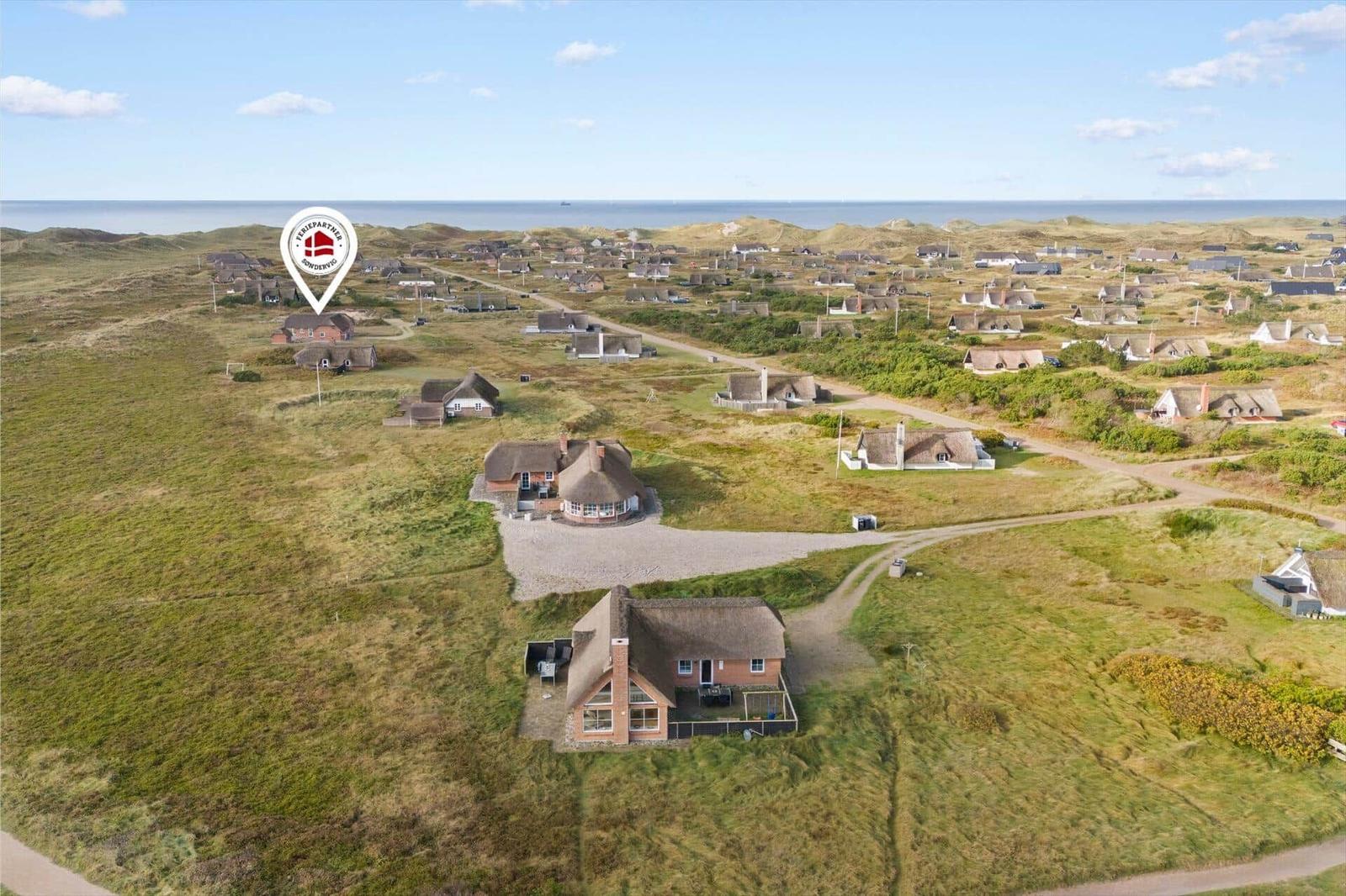 Haus mit Dach aus Stroh auf einer grünen Wiese, Blick auf das Meer.