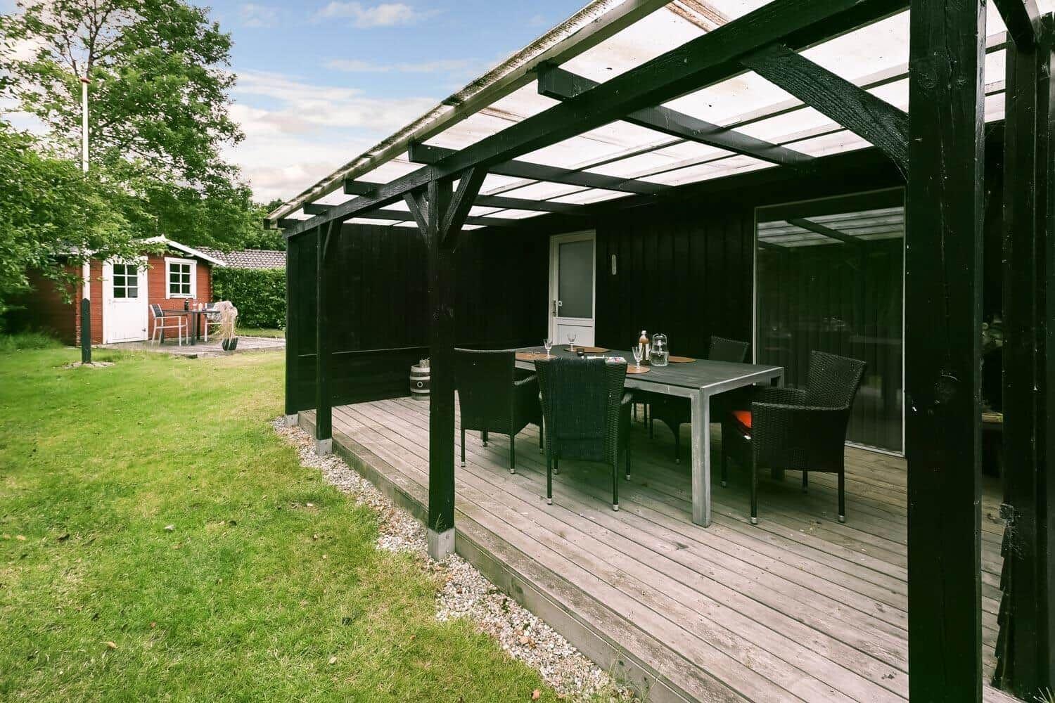 Terrasse mit Tisch und Stühlen unter einem Dach