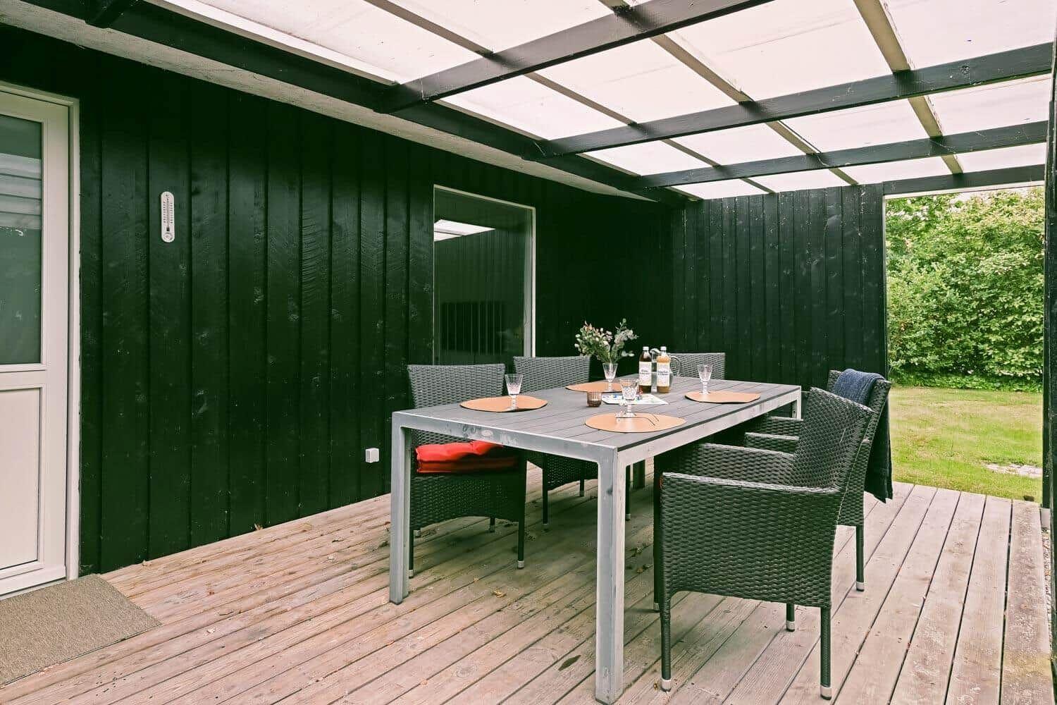 Terrasse mit Tisch und Stühlen unter Dach