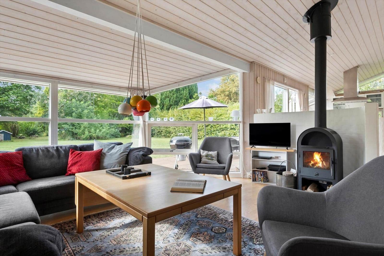 Wohnzimmer mit Sofa, Kamin und großem Fensterblick auf Garten