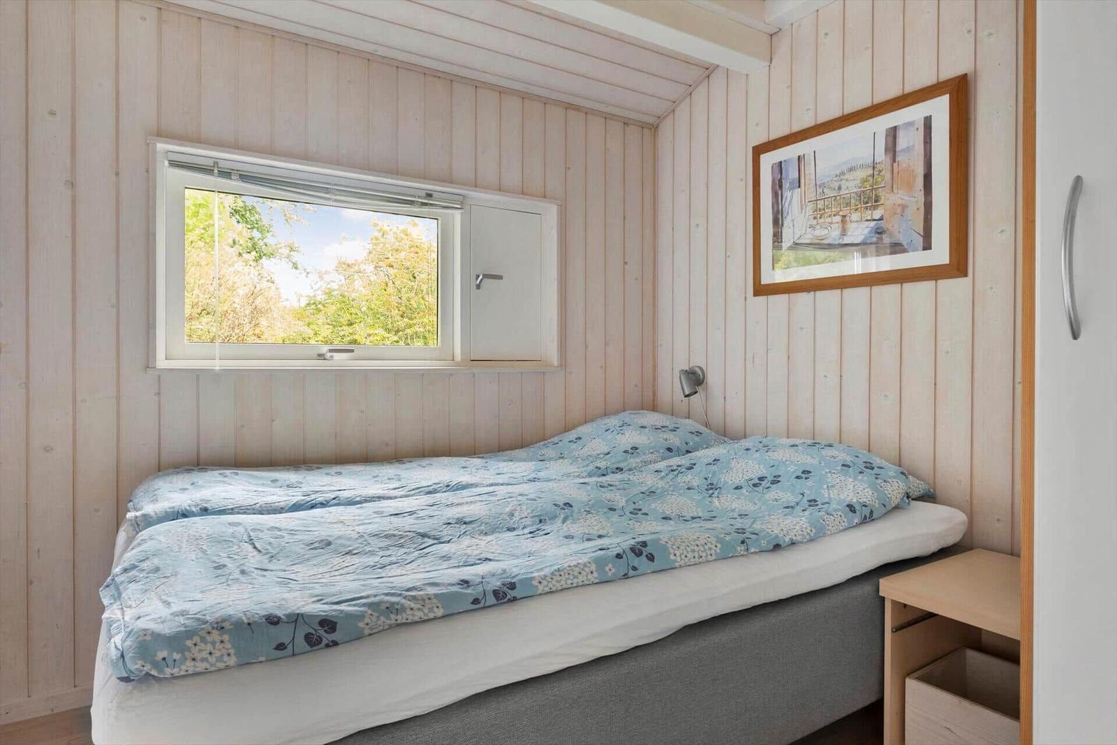 Schlafzimmer mit Bett, Fenster und Bild an der Wand.