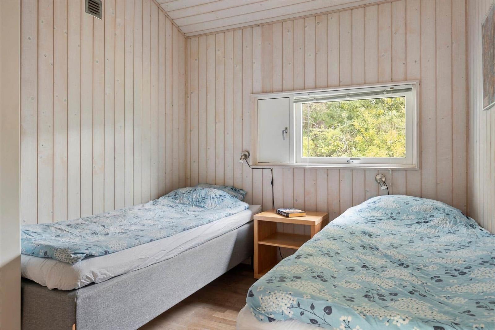 Zwei Einzelbetten mit blauen Bettwäschen und einem Nachttisch zwischen ihnen.