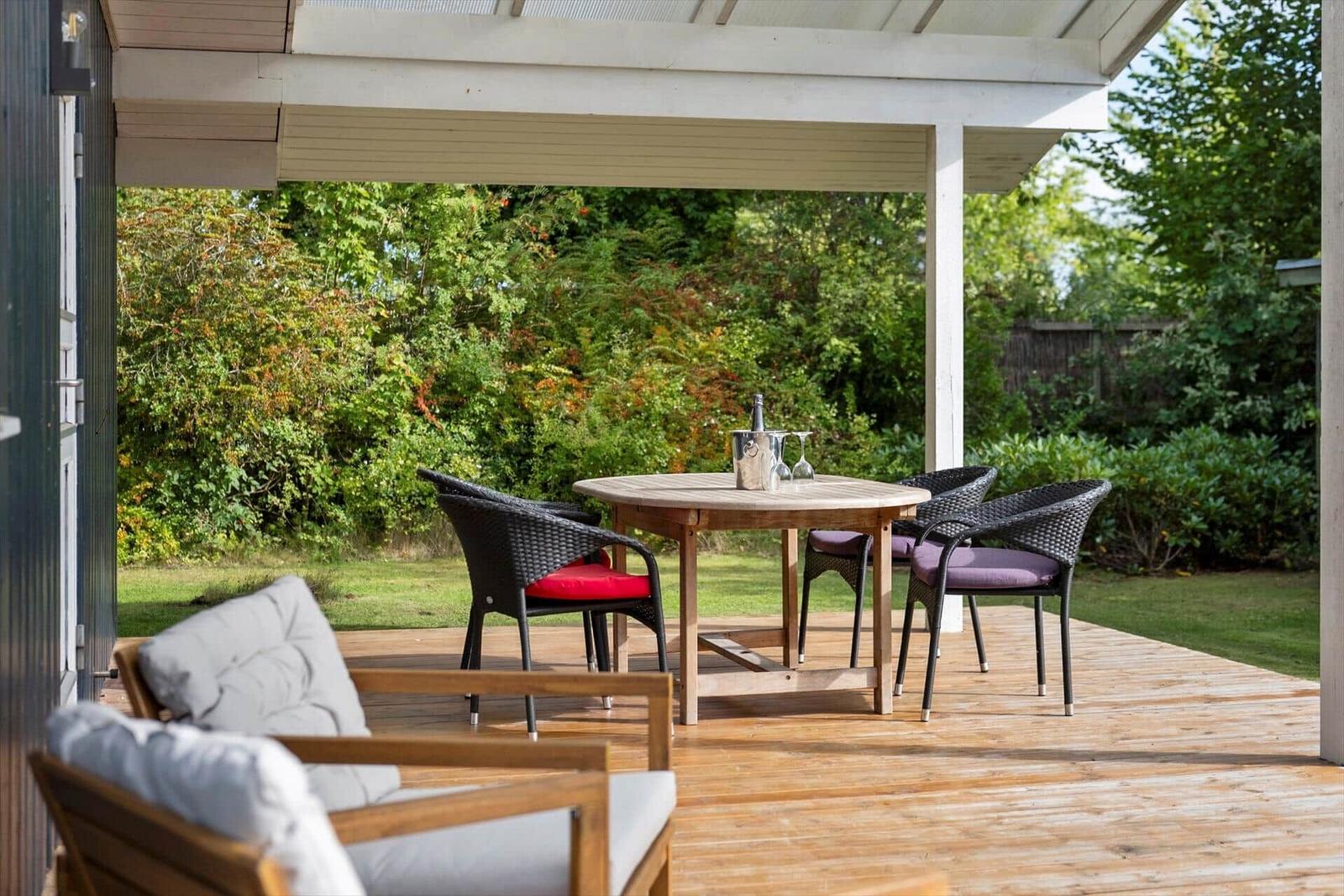Terrasse mit Tisch, Stühlen und Blick auf grünen Garten