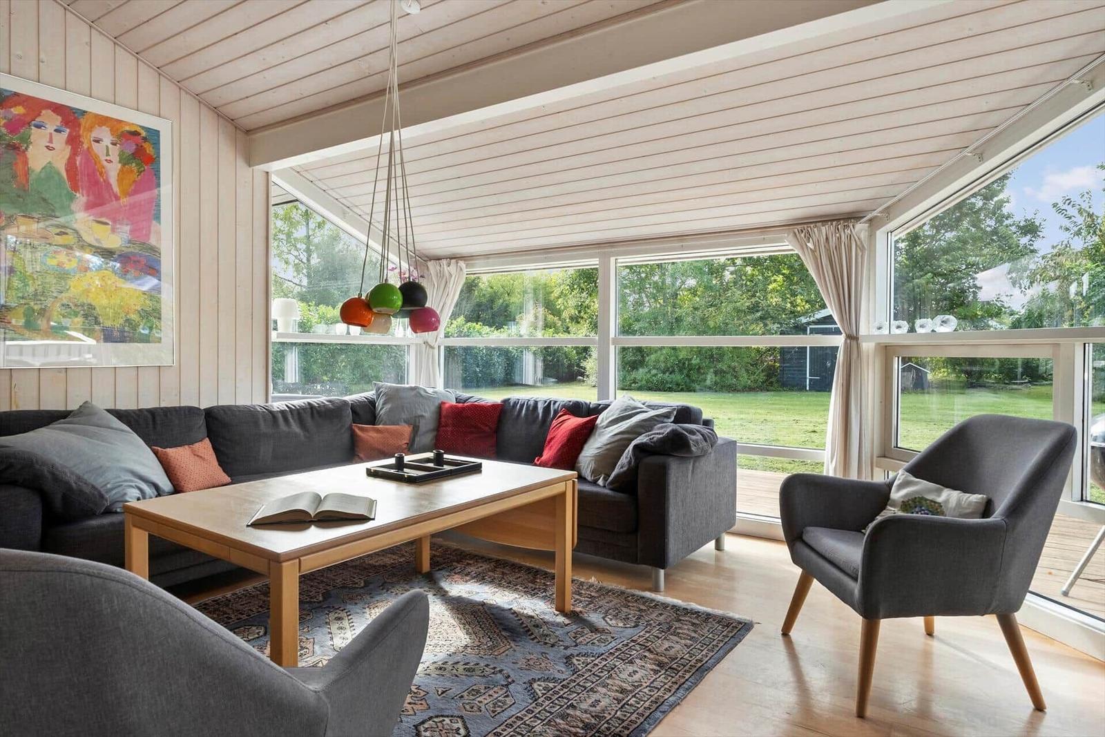 Wohnzimmer mit Sofa, Sessel und großem Fenster zum Garten
