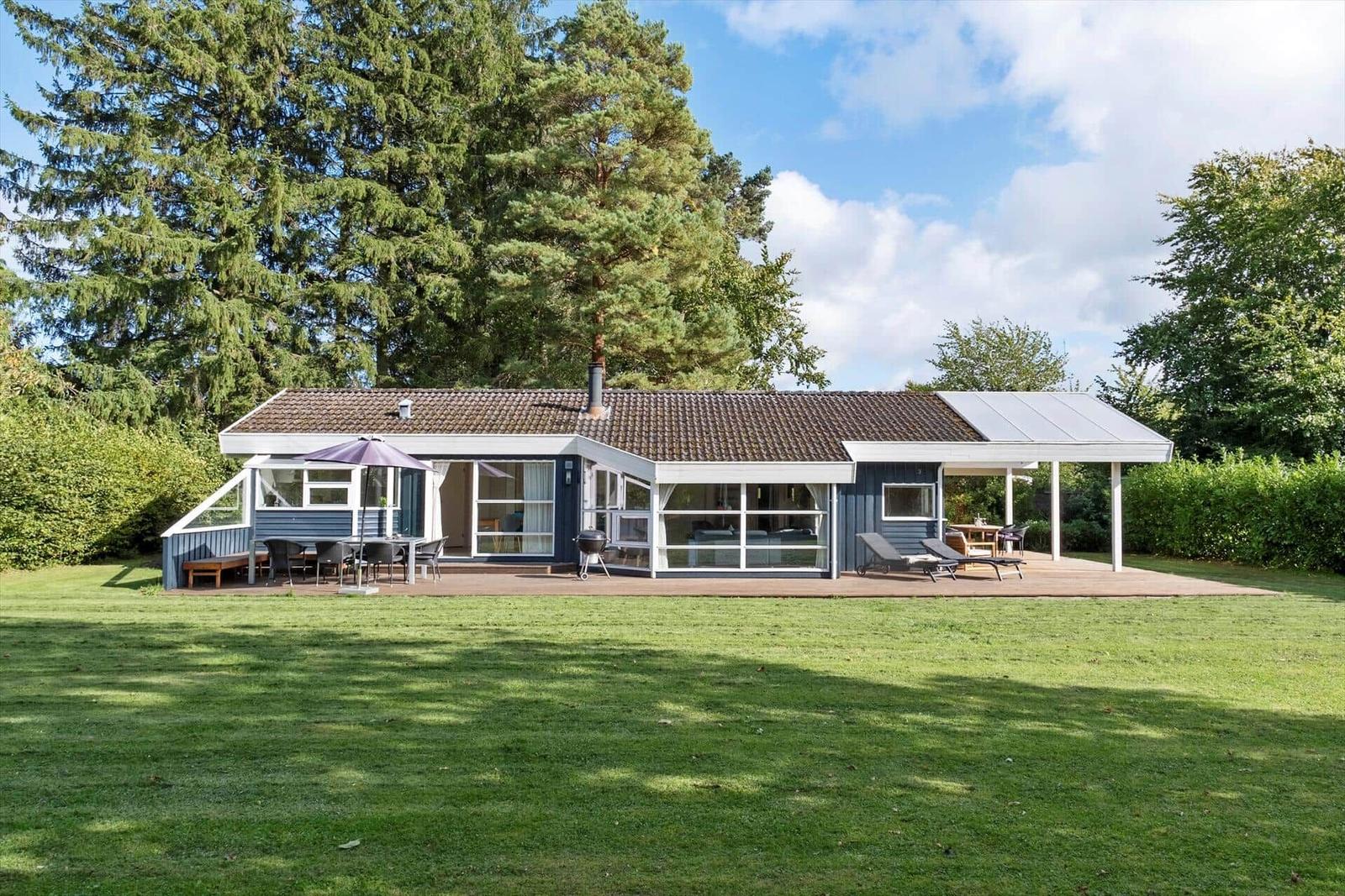 Moderne Ferienhaus mit Terrasse, Grill und Liegen im Grünen.