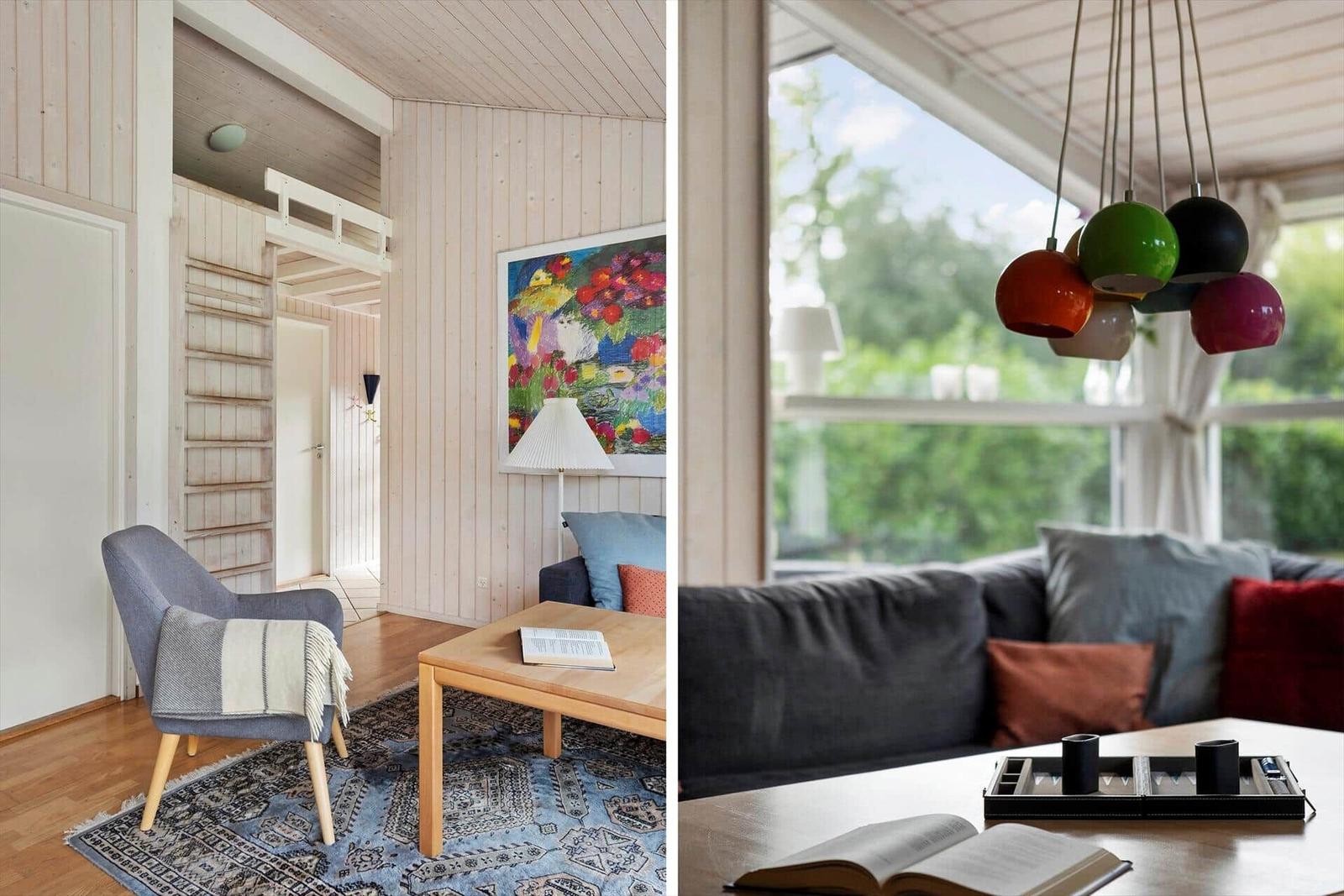 Wohnzimmer mit Sofa, Stuhl und Tisch. Fenster mit Blick auf Grün. Hängelampe mit bunten Kugeln.