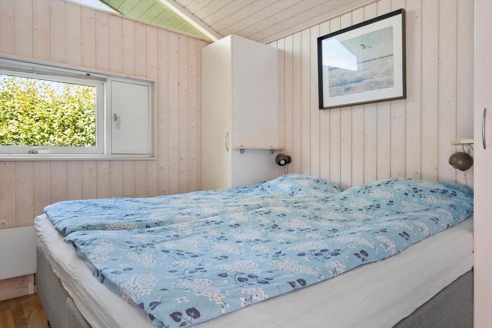 Schlafzimmer mit Bett, Fenster und Wandbild.