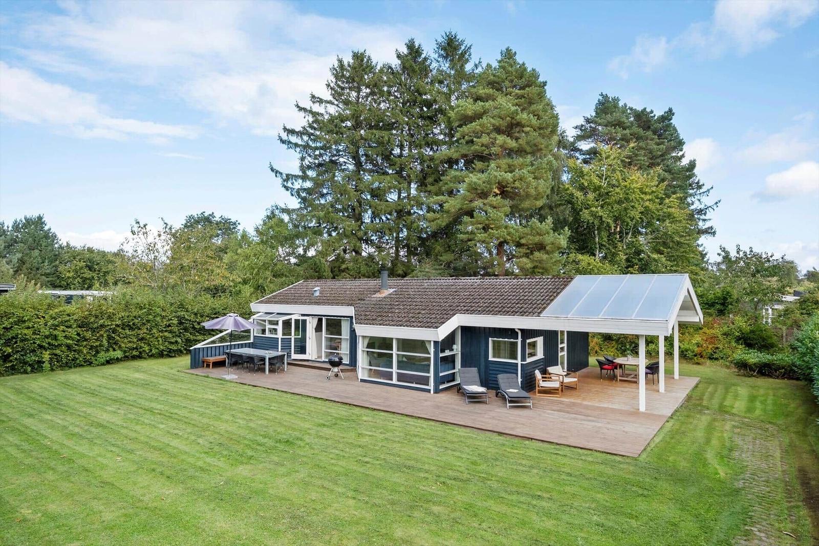 Moderne Villa mit großem Garten und Terrasse mit Liegen und Grill.