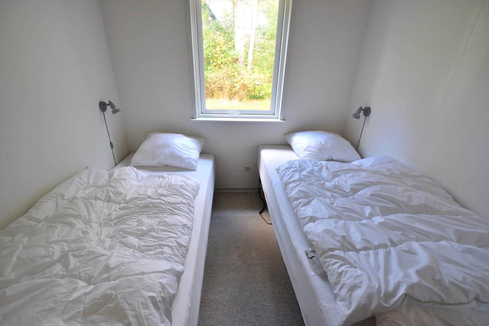 Zwei Betten mit weißen Bettwäschen und einem Fenster mit Blick auf Grün.