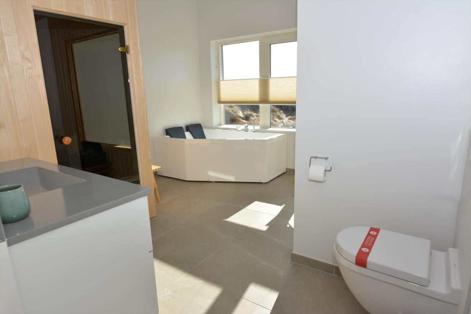 Bad mit Toilette, Waschbecken und Whirlpool unter Fenster