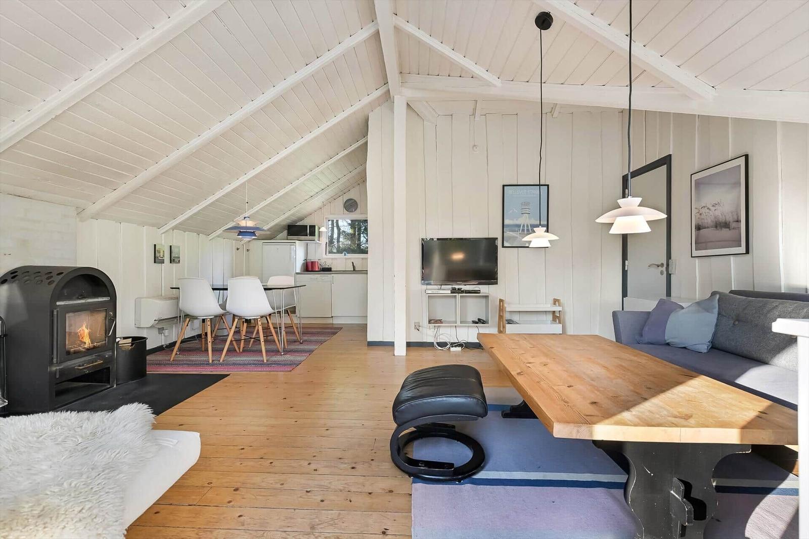 Wohnraum mit Holzfußboden, Kamin, Sofa und Esstisch. Küche im Hintergrund.