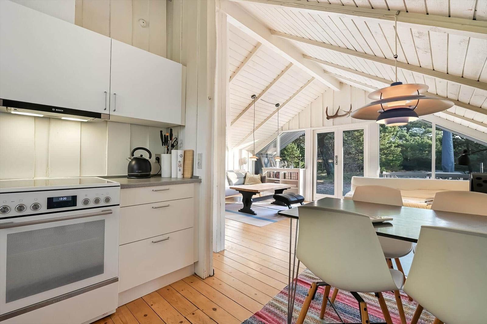 Küche mit Essbereich und Blick in Wohnzimmer mit Holzboden und großen Fenstern.