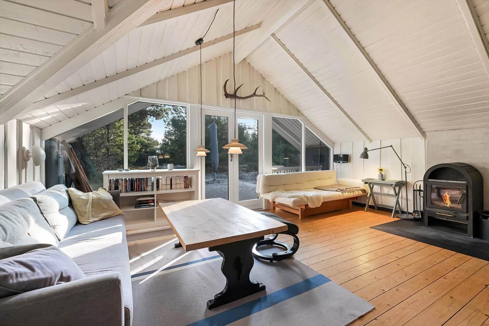 Wohnzimmer mit Holzboden, Kamin und großem Fensterblick.