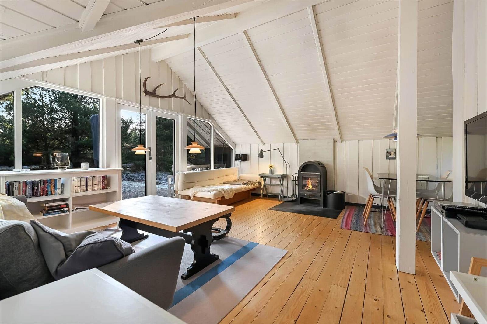 Wohnzimmer mit Holzboden, Kamin und großem Fensterblick