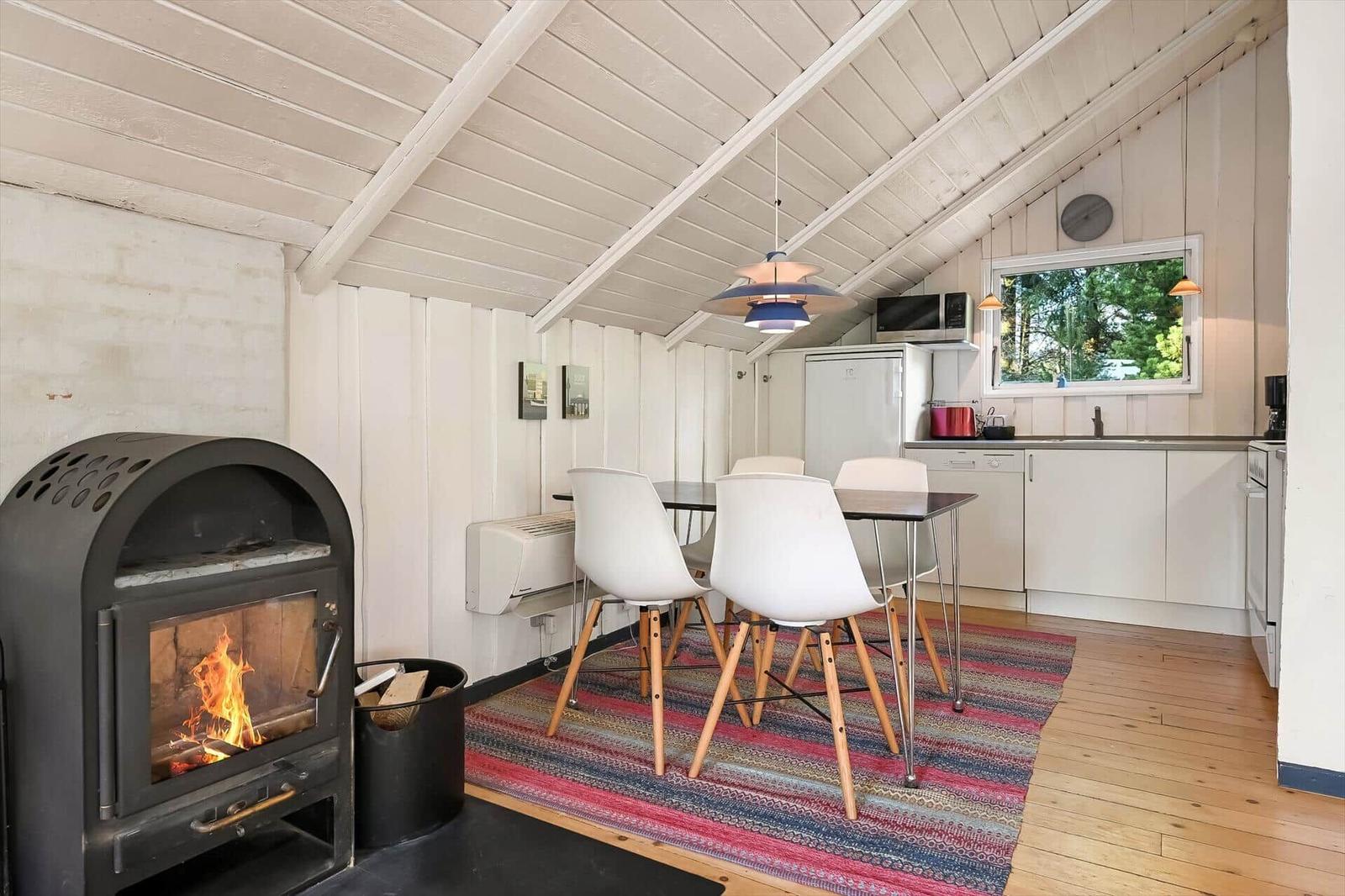 Küche mit Esstisch, Kaminofen und Fenster mit Blick auf Grün.