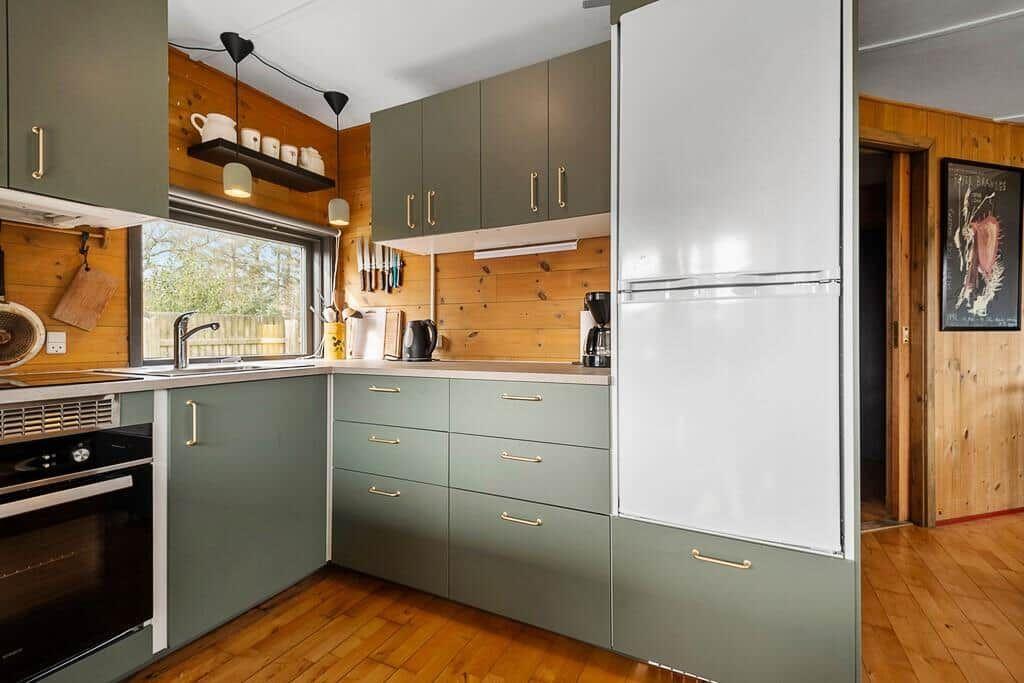 Küche mit grünen Schränken, Holzwand und Fenster