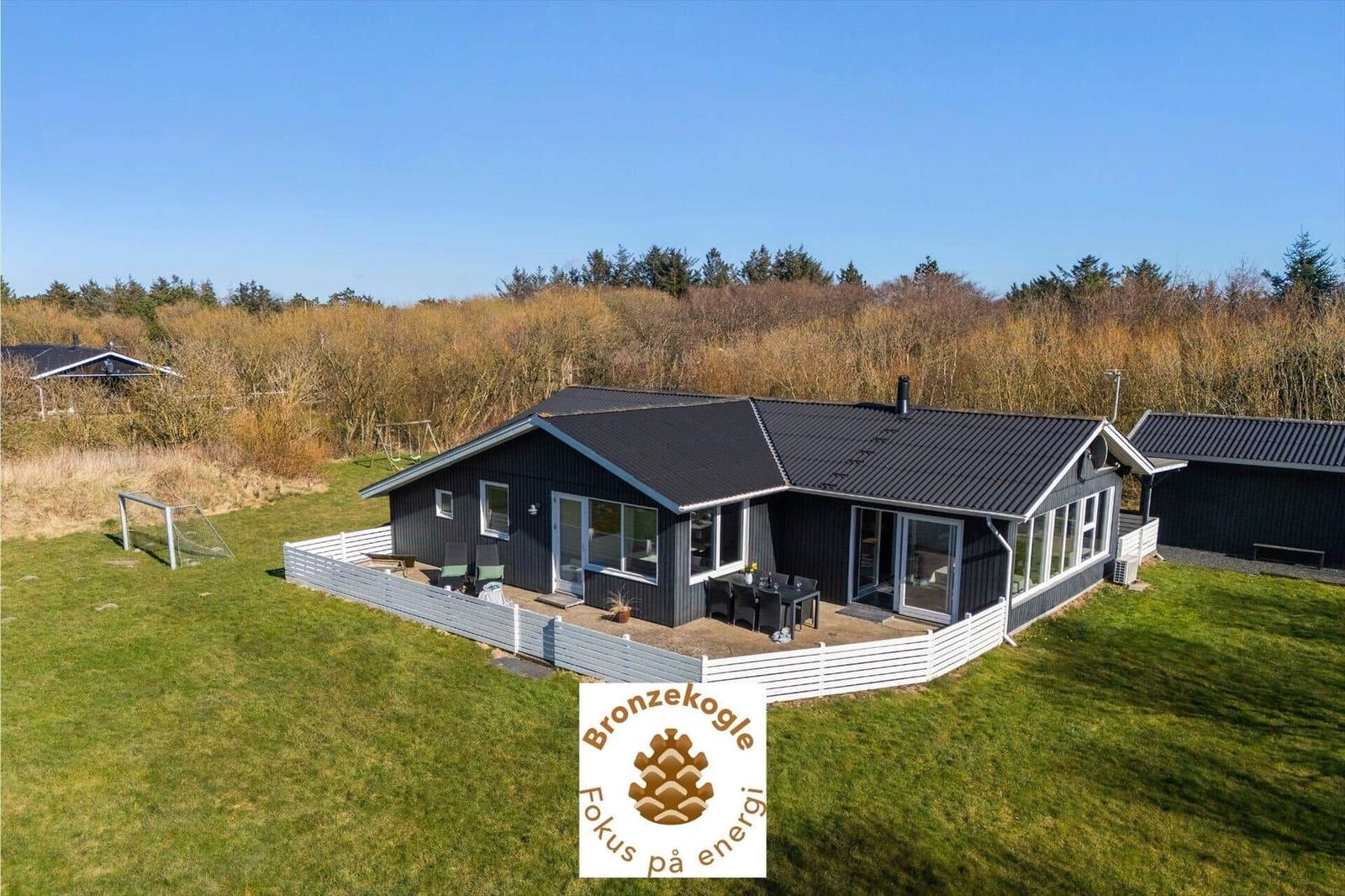 Ein modernes Haus mit Terrasse, Garten und Grillplatz. Hintergrund ist Wald.