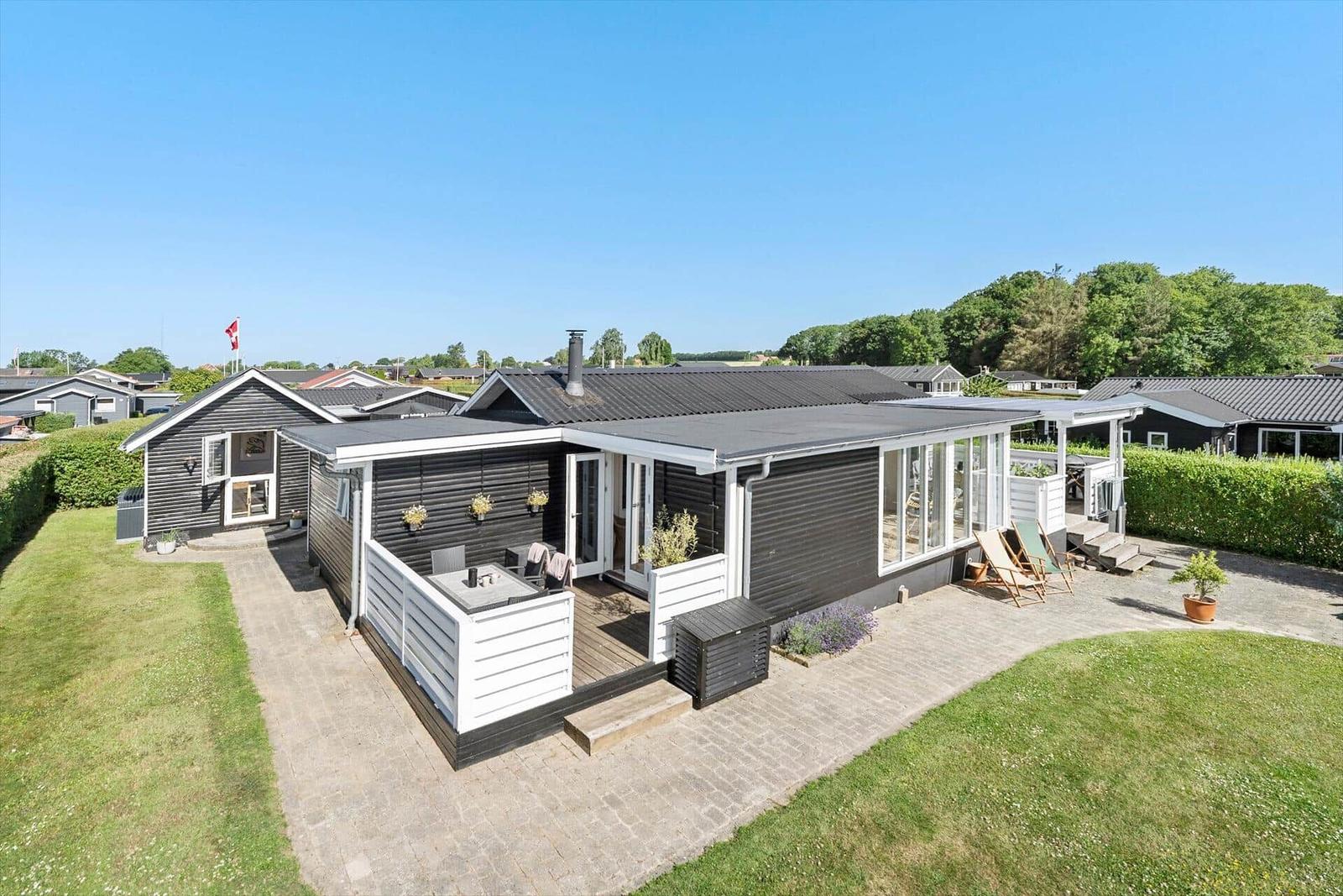 Modernes Ferienhaus mit Terrasse und Garten. Schwarze Fassade und weiße Akzente.