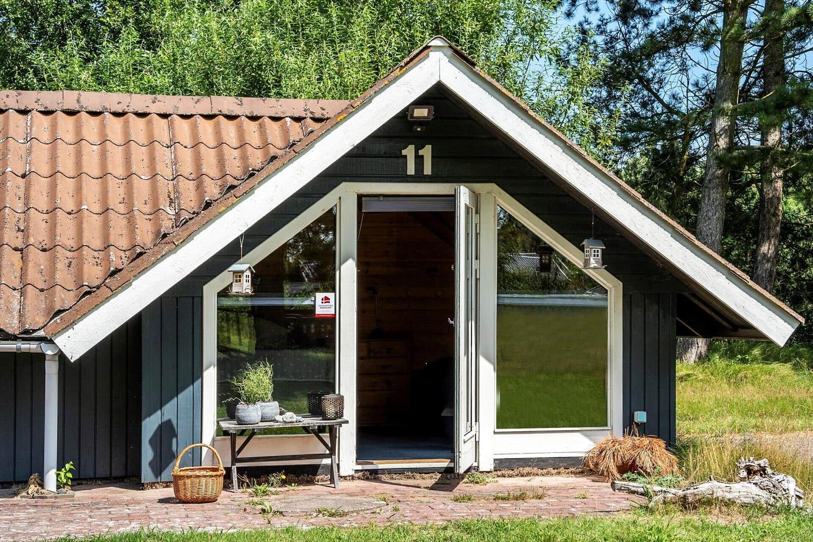 Haus mit Nummer 11, offener Eingang, Tisch mit Pflanzen und Korb vor der Tür.