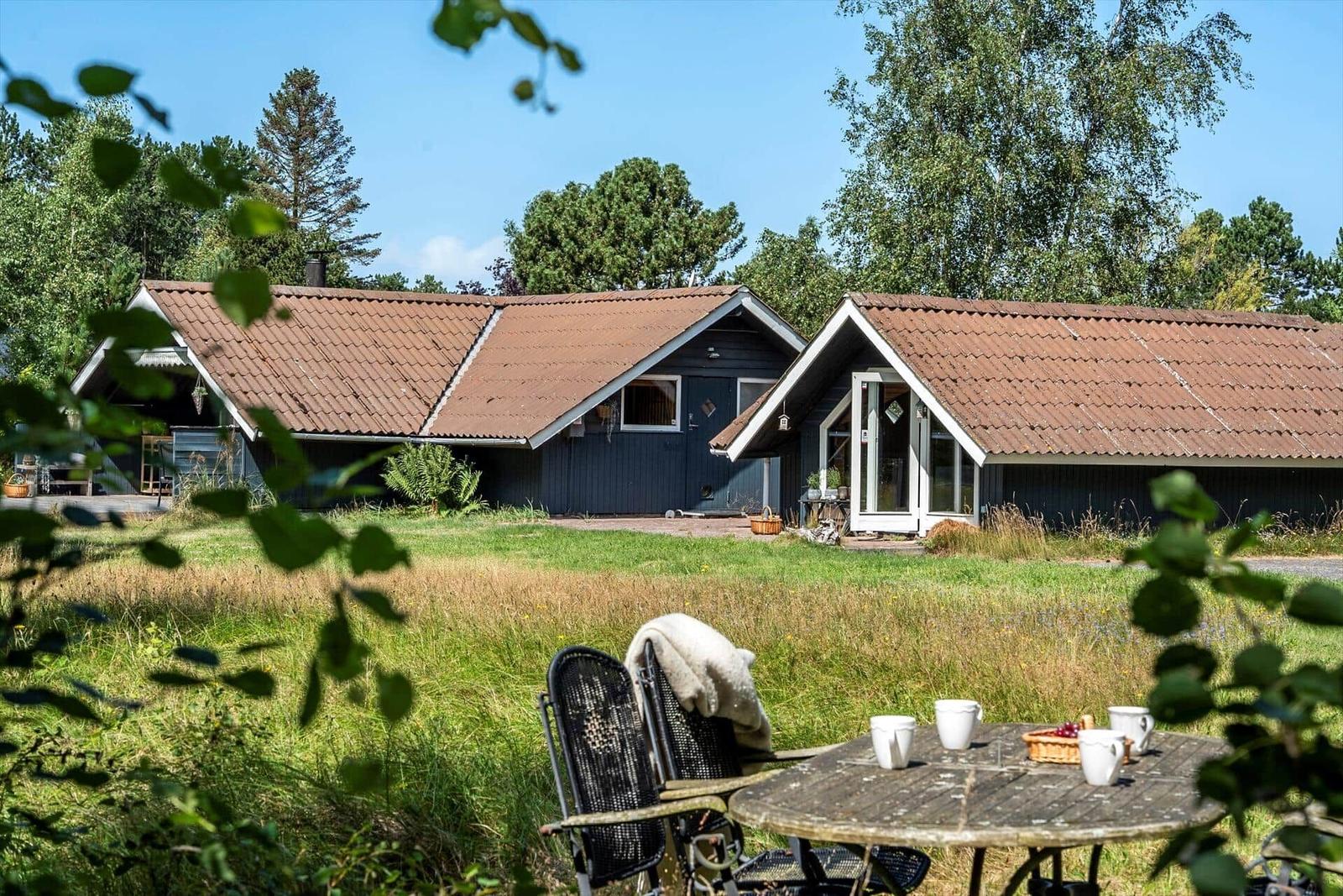 Haus mit Terrasse und Garten. Tisch mit Stühlen im Vordergrund.