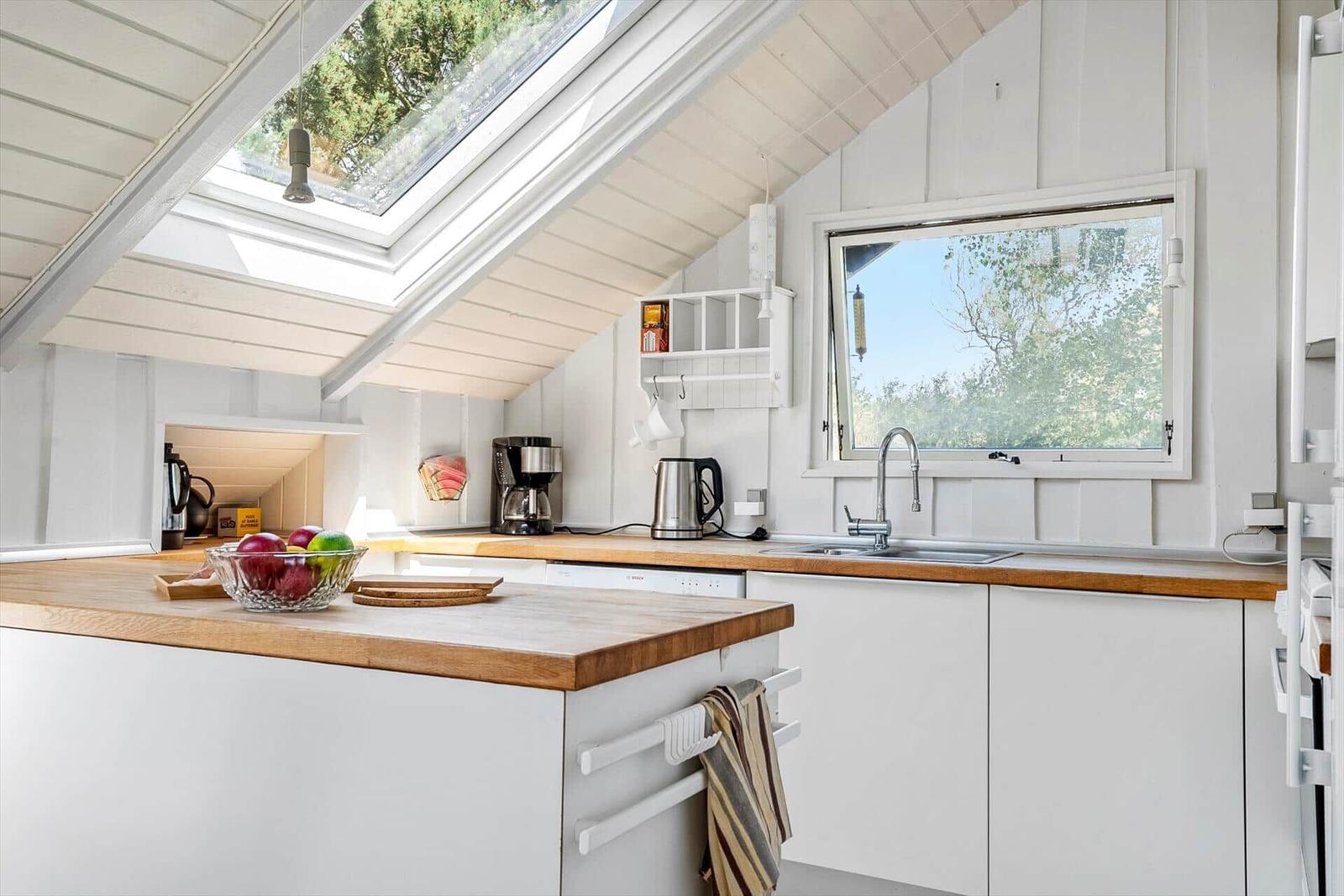 Küche mit Holz Arbeitsplatte, Fenster und Dachfenster.