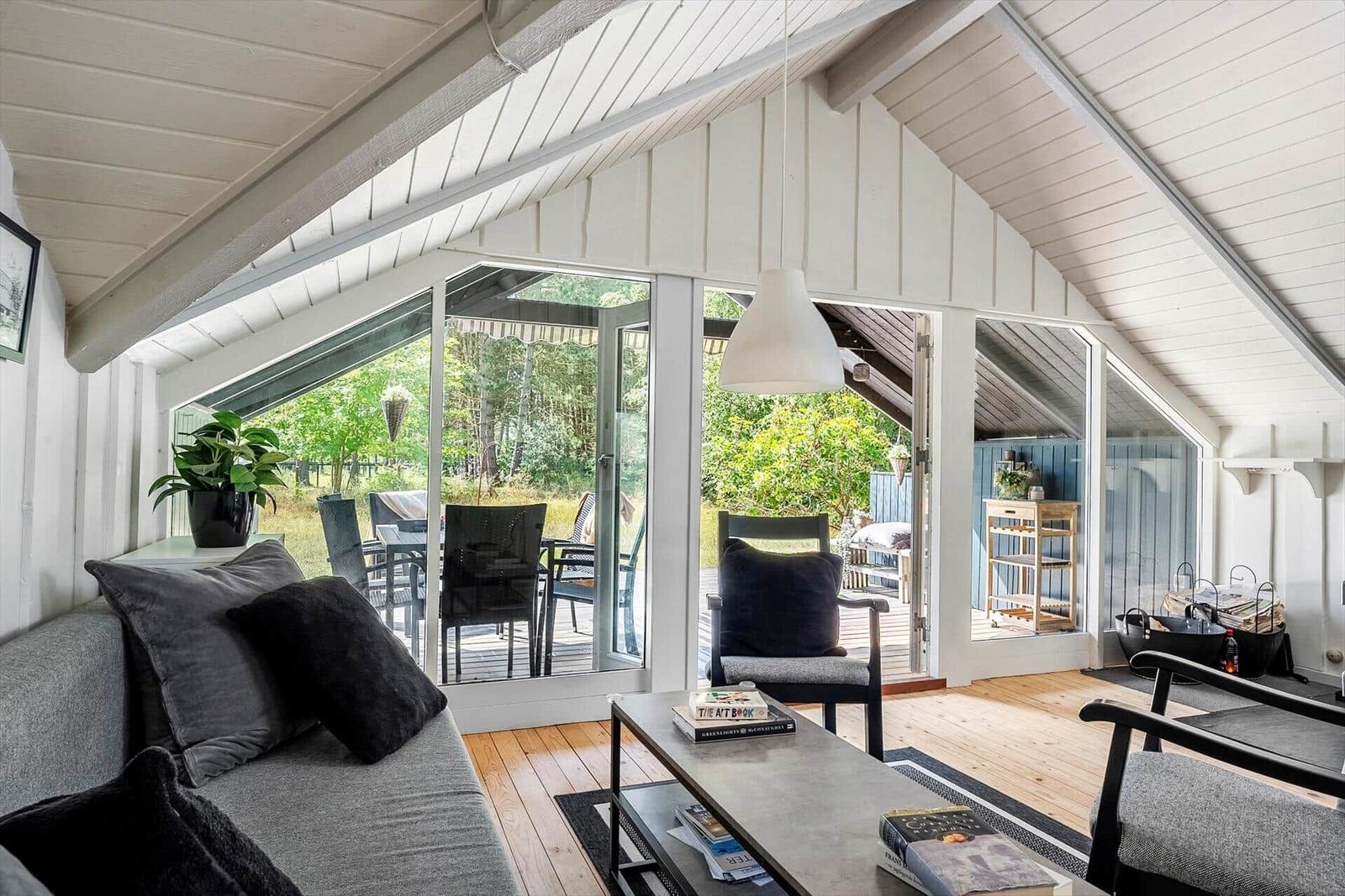 Wohnbereich mit Sofa, Sitzgelegenheiten und Glasfront zur Terrasse.