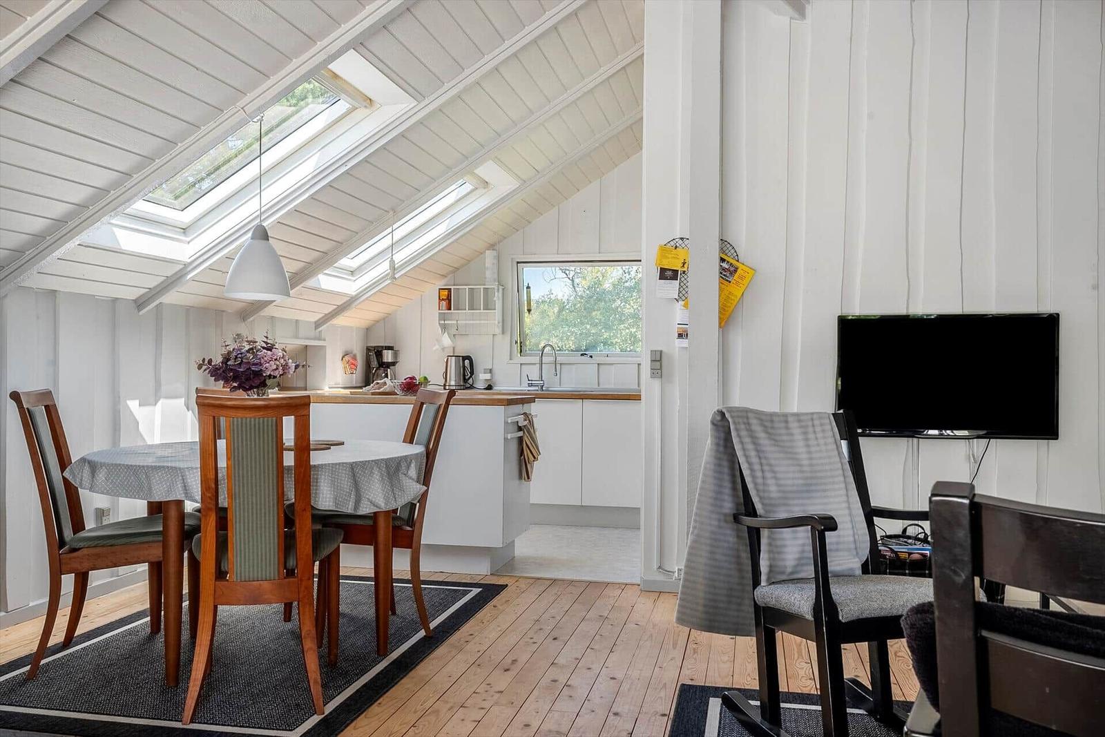 Doppelzimmer mit Essbereich, Küchenzeile und TV. Holzboden und Dachschrägen.