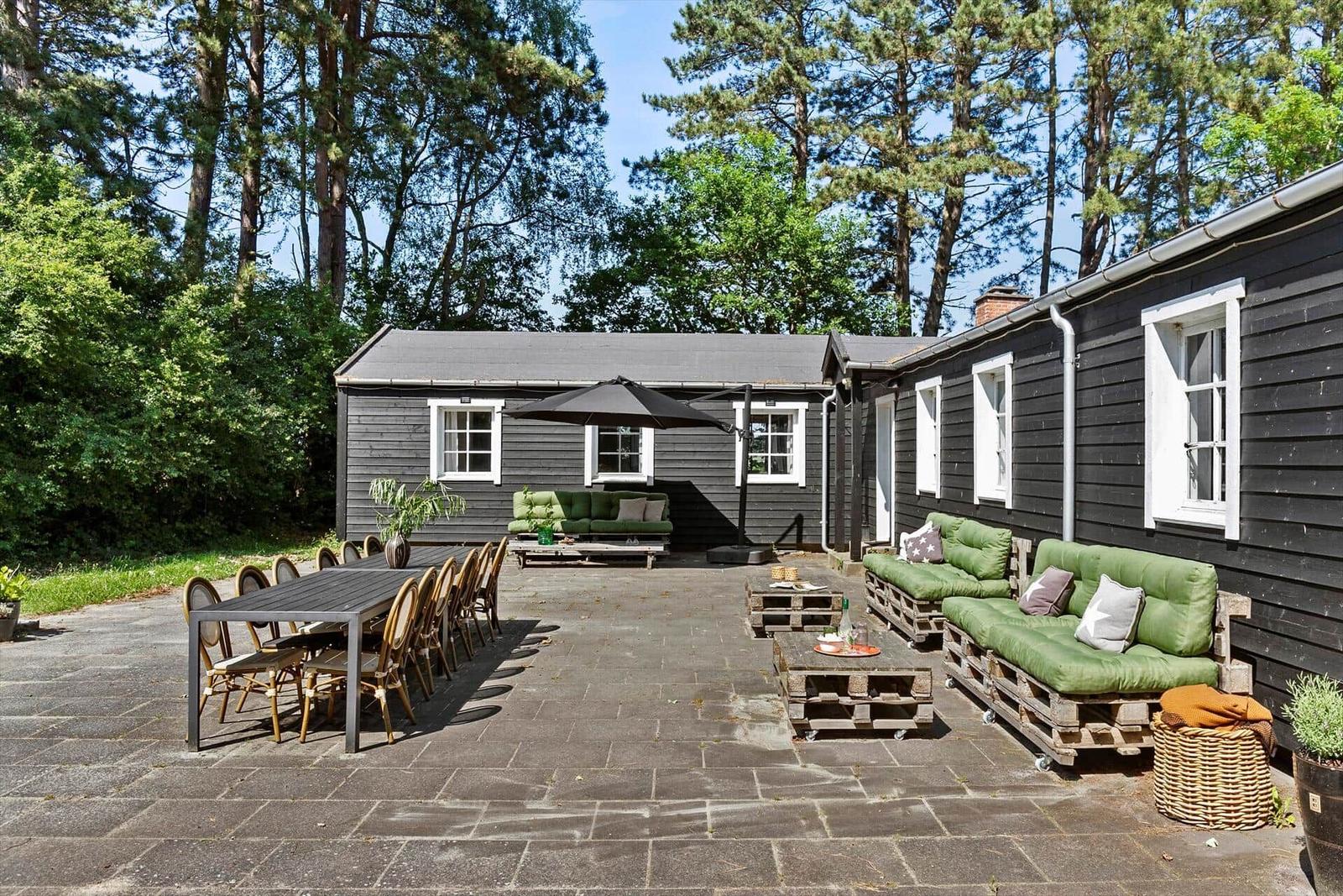 Außenbereich mit Tisch, Stühlen, Sofa und Sonnenschutz.