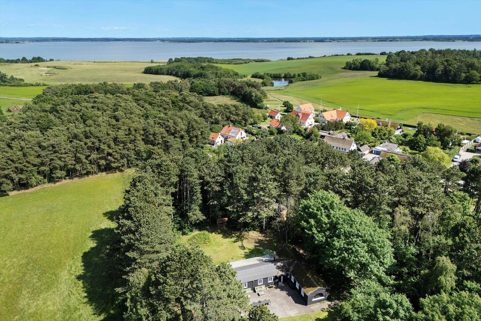 Haus im Wald mit Blick auf Felder und Wasser