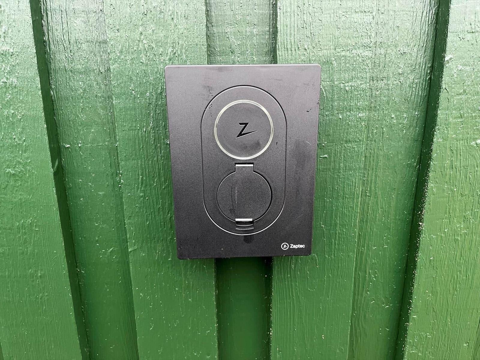Zaptec Ladestation an grüner Wand montiert