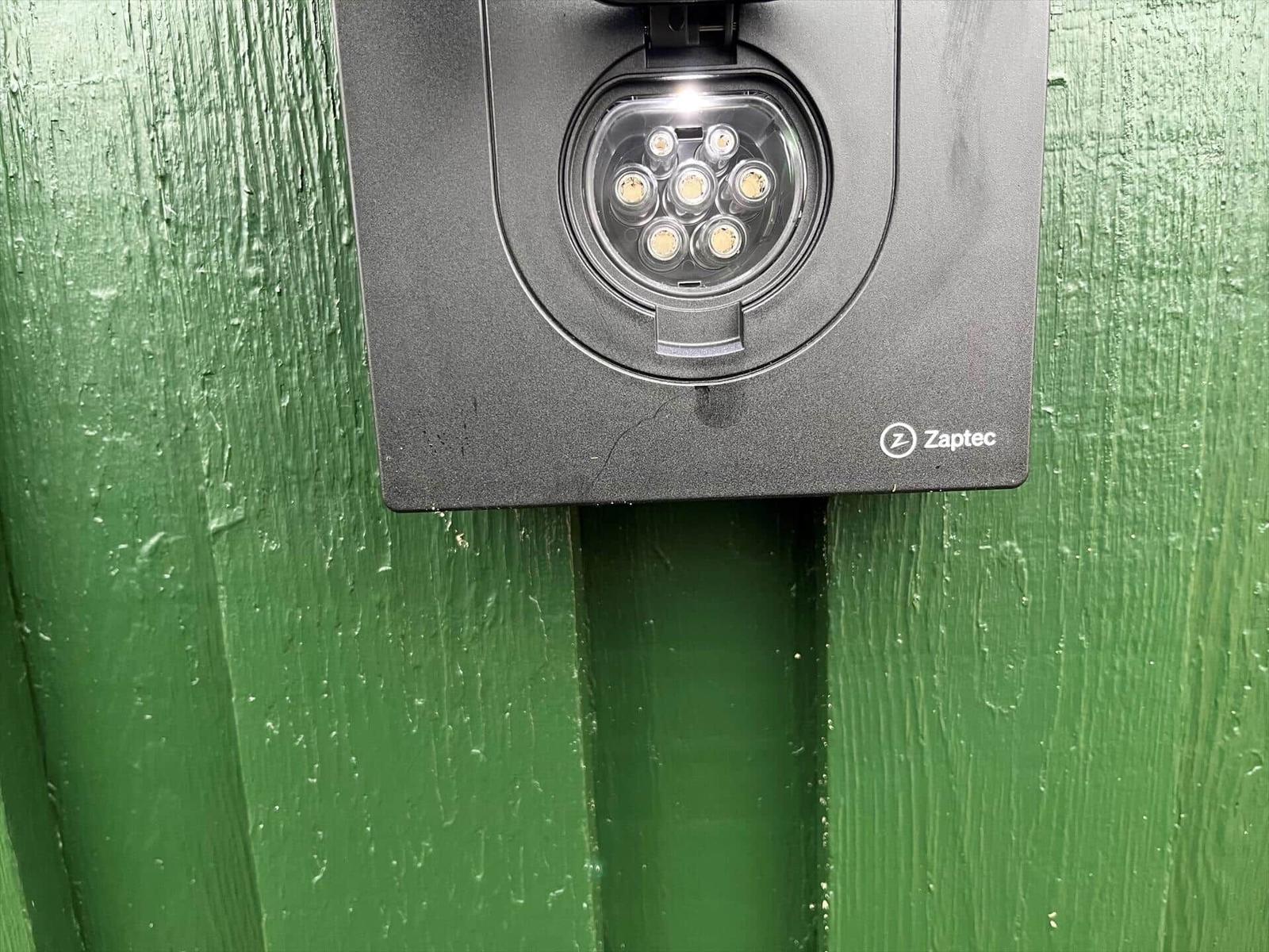 Zaptec-Kamera an grüner Holzwand montiert