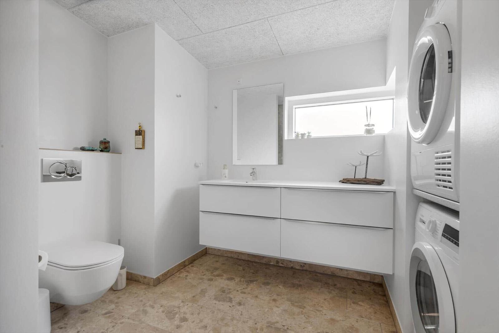 Badezimmer mit Waschmaschine und Trockner, Spiegelschrank und Toilette.