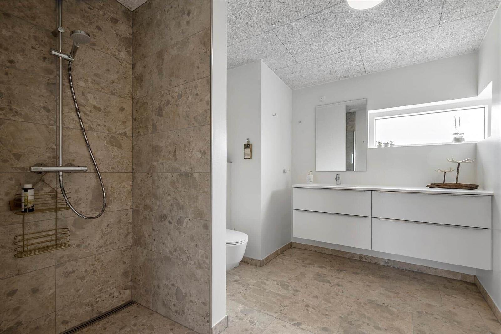 Dusche mit Steinwand, Waschtisch mit Spiegel und Fenster